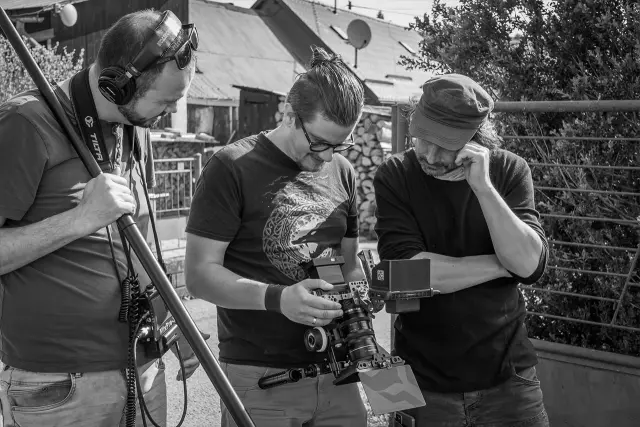 Zvukár s mikrofónom na tyči a kameraman kontrolujú záber na monitore kamery