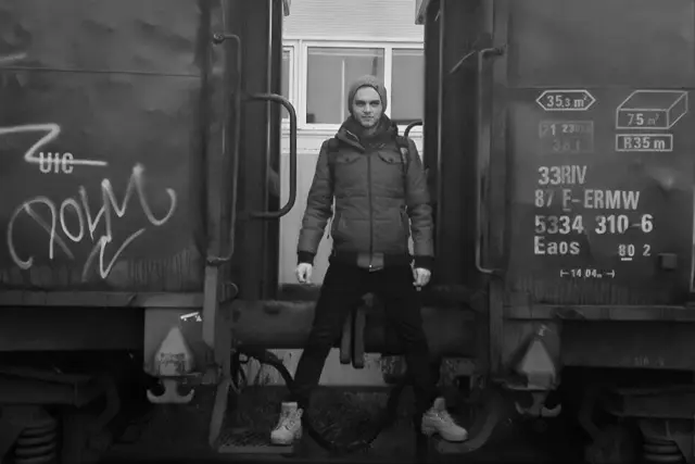 Herec stojí medzi dvoma nákladnými vagónmi